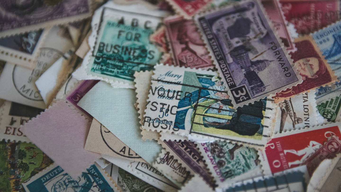 Scattered vintage postage stamps with various designs on a light surface.
