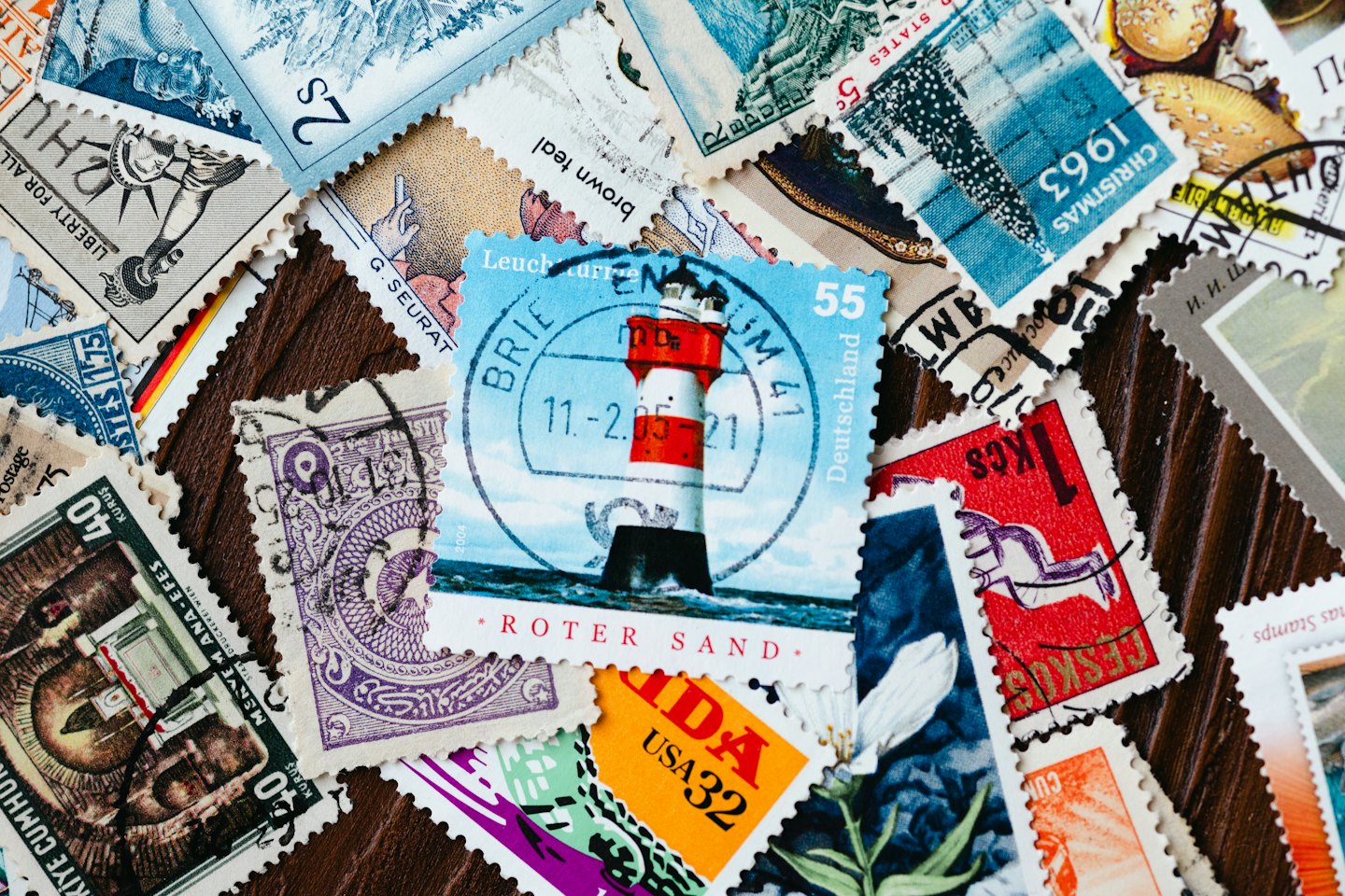 Vintage postage stamps from different countries scattered on a wooden table.