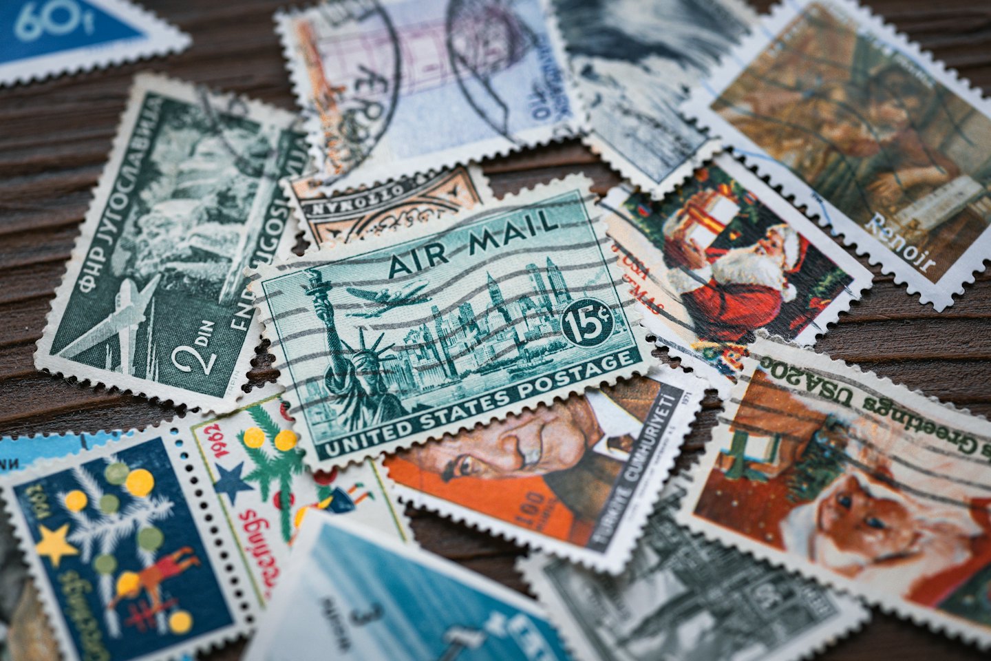 Vintage postage stamps scattered across a dark wooden table.