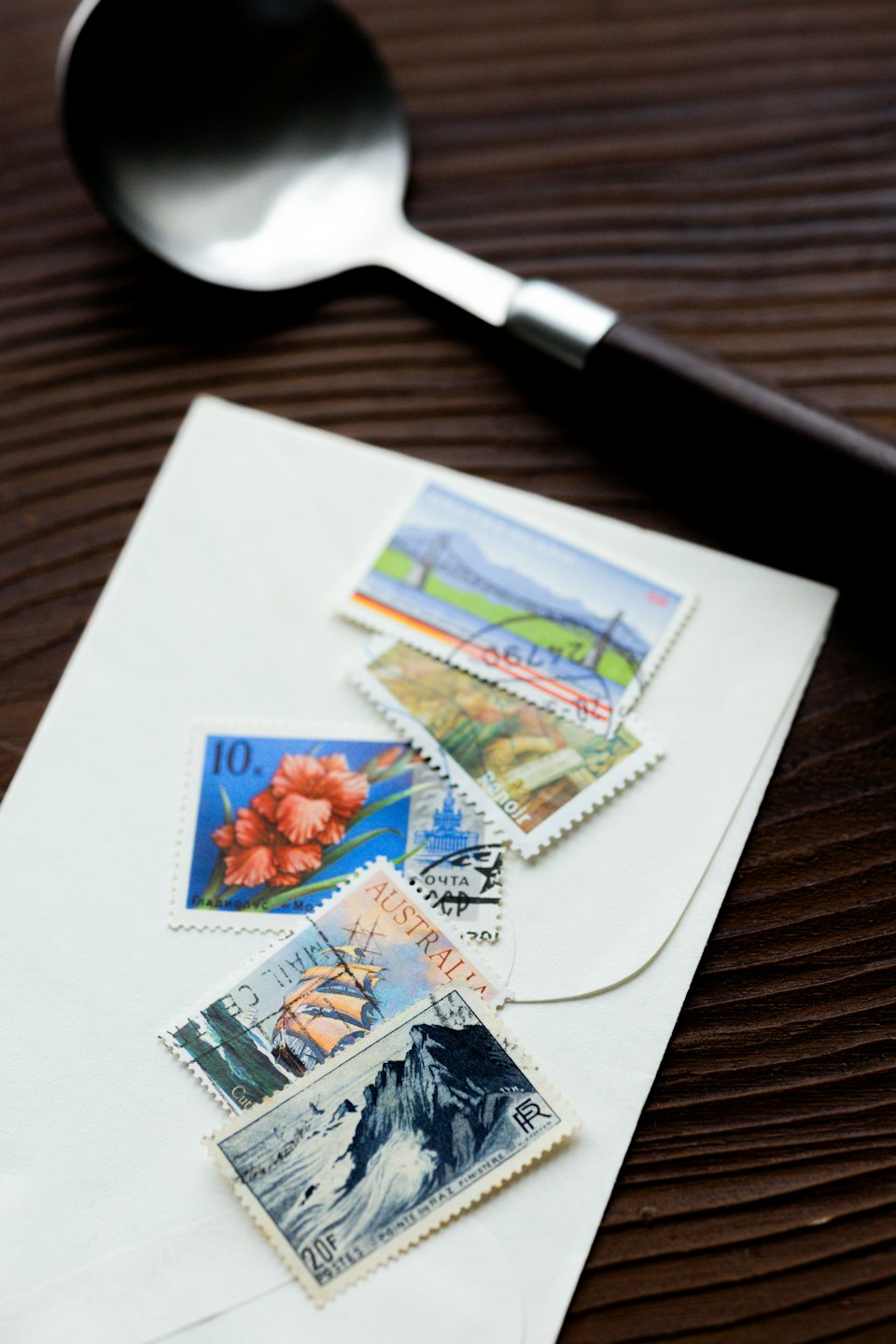 Vintage postage stamps arranged on a white envelope on wood.