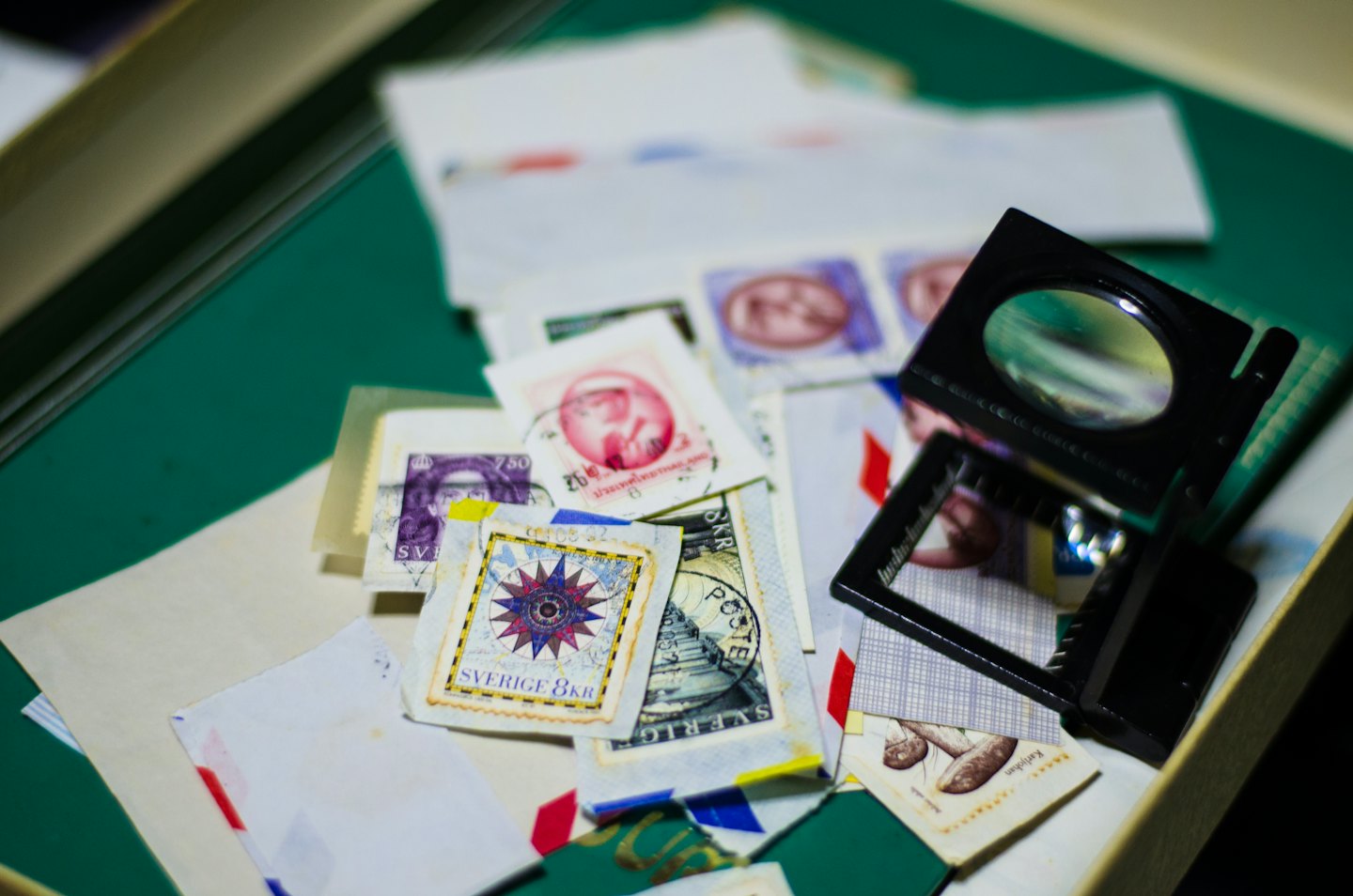 Vintage postage stamps and a magnifying glass on a table.