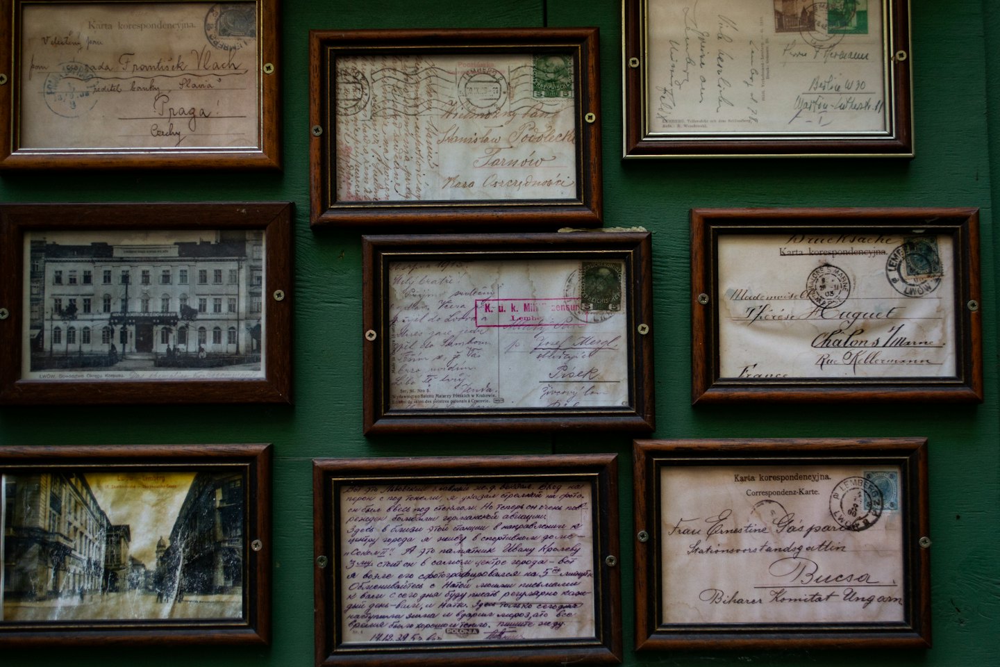 Nine vintage postcards in wooden frames hung on a wall.