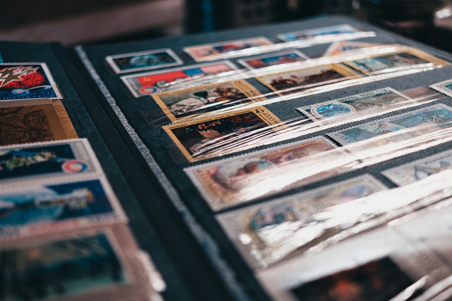 An open album displays various postage stamps in plastic sleeves.